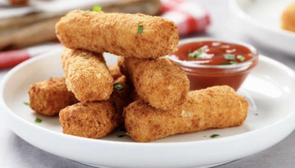 Assiette de bâtonnets de fromage croustillants servis avec une sauce marinara dans un petit bol.